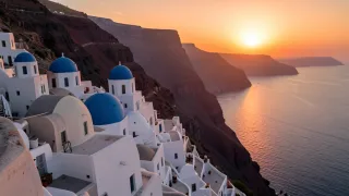Whitewashed Santorini houses with blue domes terraced down a caldera cliff against a glowing orange sea sunset